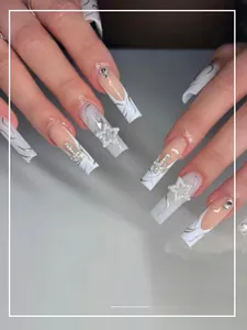 Macro shot of long pink and white press-on nails with 3D pearls, stars and cross charms
