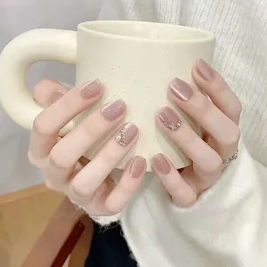 Close-up of nude pink cat-eye press-on nails with silver glitter and tiny rhinestones