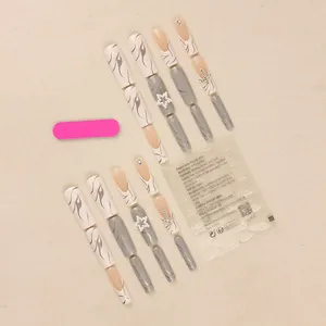 Long white press-on nails set with star diamonds, flame patterns, and pearls on beige cloth