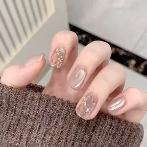 Detailed view of nude cat-eye press-on nails with gold foil and shimmer on hands