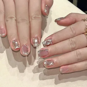 Close-up of pink press-on nails with silver foil, glitters and white pearl accents