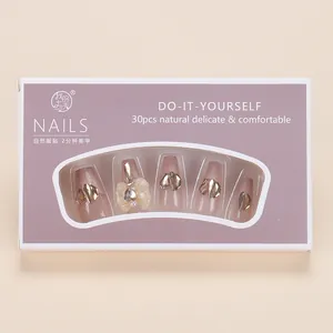 Detail of press-on nails with 3D bows, gold glitter, and pearl pink finish in box