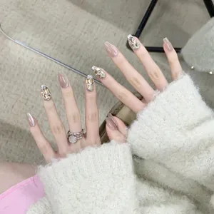 Close-up of coffin-shaped press-on nails with nude polish and luxury rhinestone accents