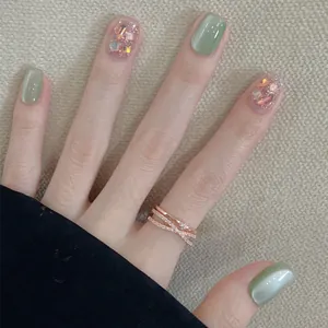 Détail de faux ongles œil de chat vert nude avec paillettes et bague en or rose