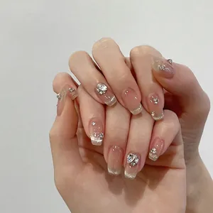 Macro shot of milky pink press-on nails with silver french tips and sparkling crystals