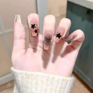 Detail of long trapezoid press-on nails with black stars and a 3D heart charm
