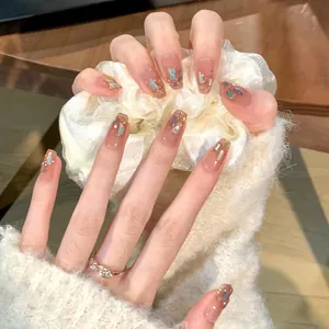 Close-up of nude pink press-on nails with blue glitter and sparkling sequins detail