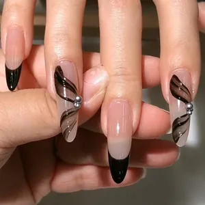 Détail de faux ongles amande longs avec pointes noires et perles métalliques argentées