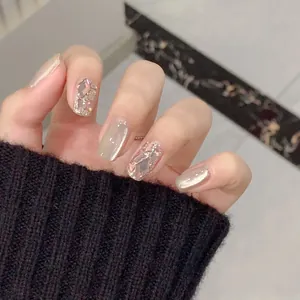 Detail of luxury press-on nails with champagne cat-eye effect and large rhinestone accents