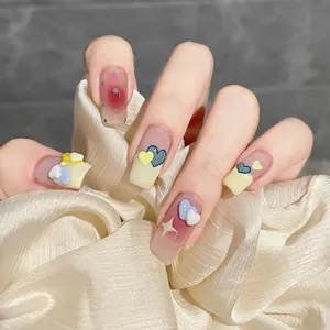 Close-up of handmade press-on nails with 3D hearts and starry patterns on a satin cloth