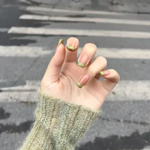 French press-on nails featuring green plaid tips and nude base on model's hand