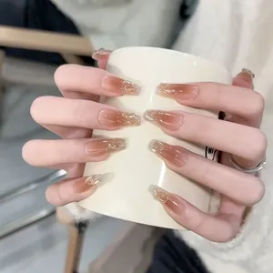 Close-up of long coffin nails with caramel gradient and gold leaf details on hands
