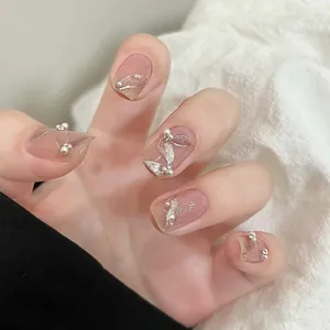 Macro detail of nude pink press-on nails with silver glitter leaf designs and pearls