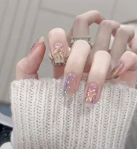 Detail of pink press-on nails with golden floral patterns and sparkling glitter finish