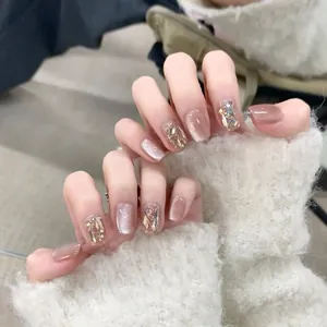 Detail of luxury press-on nails with champagne gold cat-eye effect and rhinestone accents