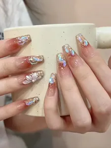 Detail von Ballerina-Nägeln mit rotbraunem Verlauf, Goldglitzer und weißer Blume