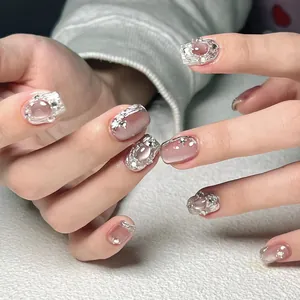 Detail of pink cat-eye press-on nails with 3D silver relief lines and pearl rhinestones
