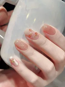 Nahaufnahme von nude-rosa Klebenägeln mit 3D-Kirschen und feinem silbernem Glitzer