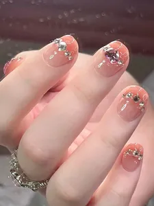 Makro-Detail von nudefarbenen Farbverlauf-Nägeln mit lila Herz-Edelsteinen und Strass