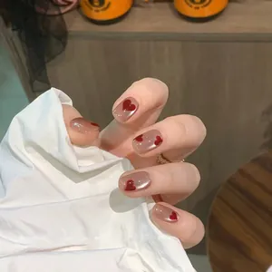 Vista macro di unghie glitter marroni con motivi a cuore rosso su unghie finte corte