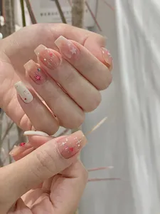 Details von nude-rosa Farbverlauf-Kunstnägeln mit silbernen Sternen und roten Herzen