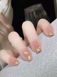 Nahaufnahme von quadratischen Kunstnägeln mit rosa Farbverlauf, Goldfolie und Strasssteinen