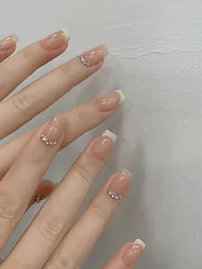 Makro-Detail von Nude French Press-On Nägeln mit weißen Spitzen und Silber-Strass