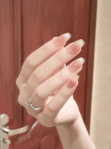 Nahaufnahme von rosa Ombré-Kunstnägeln mit Glitzerakzenten und einem Silberring