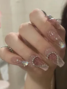 Nahaufnahme der Mandel-Klebenägel mit rosa Glitzer, Strasssteinen und Perlenakzenten