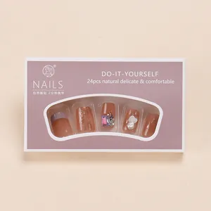 Detail of nude gradient press-on nails with purple rhinestones and gold foil flakes
