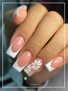Macro shot of French tip press-on nails with white flower and subtle rhinestone detail