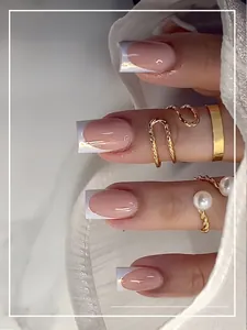 Dettaglio delle unghie finte French rosa nude con punte bianche e sottili linee dorate