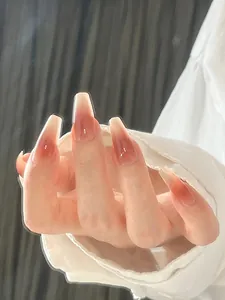 Dettaglio di unghie finte lunghe a ballerina con sfumatura rosso-rosa e finish lucido