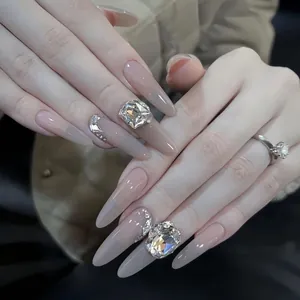 Makro-Detail von Nude-Farbverlauf-Stiletto-Nägeln mit funkelnden großen Kristall-Diamanten