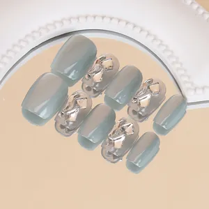 Detail van grijze cat-eye kunstnagels met 3D-steentjes op een gouden spiegel