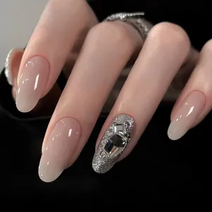 Détail d'ongles ombrés rose nude avec paillettes argentées et accents de strass 3D