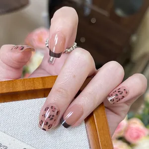Détail de faux ongles brillants avec motif léopard et pointes françaises café foncé