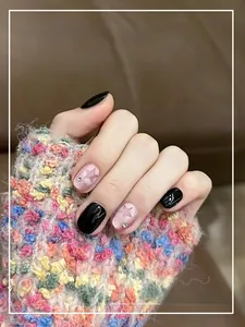 Close-up of black and pink cat-eye press-on nails with star patterns and small rhinestones