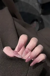 Detail of pink-to-purple gradient press-on nails with 3D heart charms and glitter