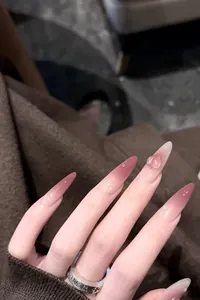 Detail of long stiletto press-on nails with pink gradient and 3D heart water drops