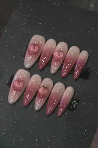 Detail of pink gradient almond press-on nails with 3D peach hearts and water droplets