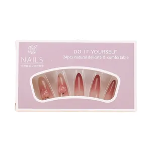 Pink gradient almond press-on nails with 3D peach charms in a purple retail display box
