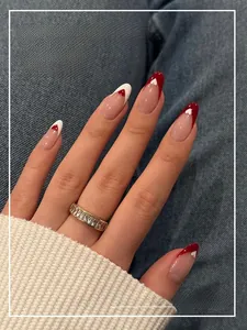Close-up of long almond press-on nails with red and white heart patterns and French tips