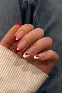 Detail of red and white heart-shaped French tip press-on nails in oval shape