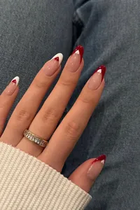 Detail of almond-shaped press-on nails with red heart French design on a denim background