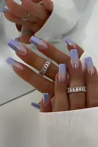 Close-up of long coffin press-on nails with purple gradient and glossy pearl finish