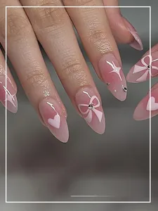 Macro detail of almond-shaped pink gradient press-on nails with bow and heart designs