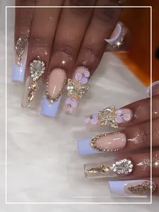 Détail de faux ongles lavande avec papillons 3D dorés, strass et perles élégantes