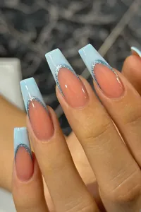 Macro detail of long coffin nails with blue French tips and blue glitter decoration
