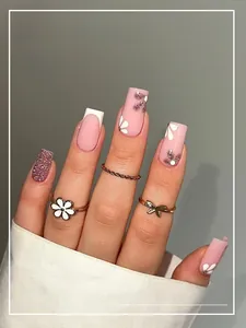 Détails de faux ongles courts French avec motifs floraux et finition pailletée brillante